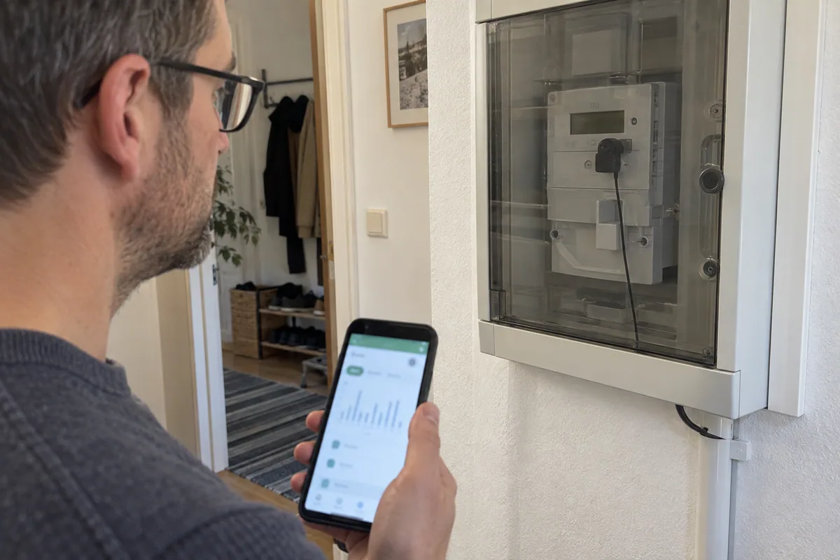 Optischer Lesekopf an einem digitalen Stromzähler hinter der geschlossenen Schranktür.